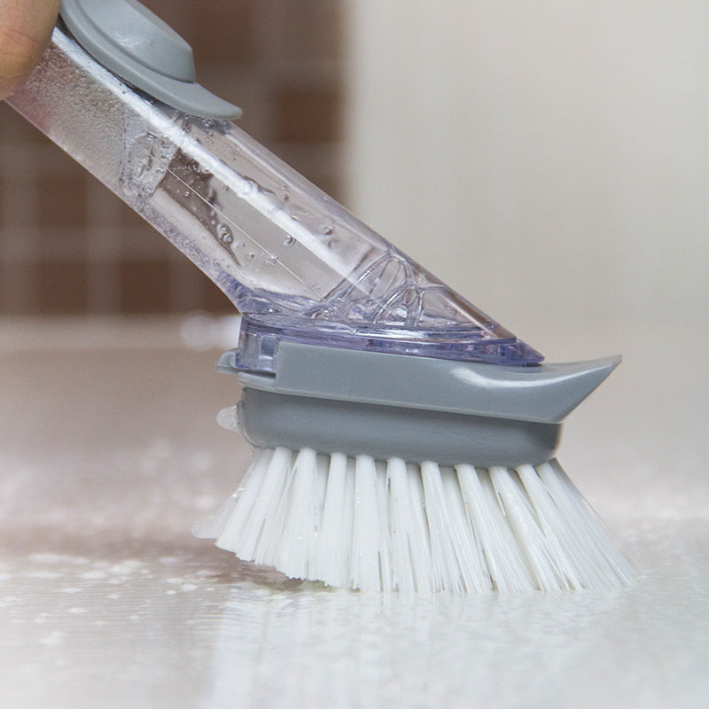 Gray dishwashing brush with bristles and a clear handle cleaning a surface.